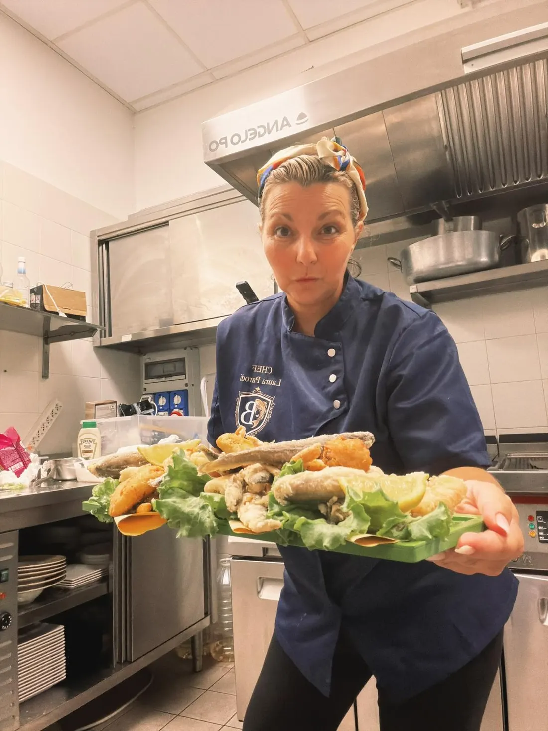 La chef Laura in cucina, con la divisa del Blue e un vassoio di pesce